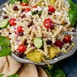 a bowl of greek pasta salad with fresh pitas sitting by it