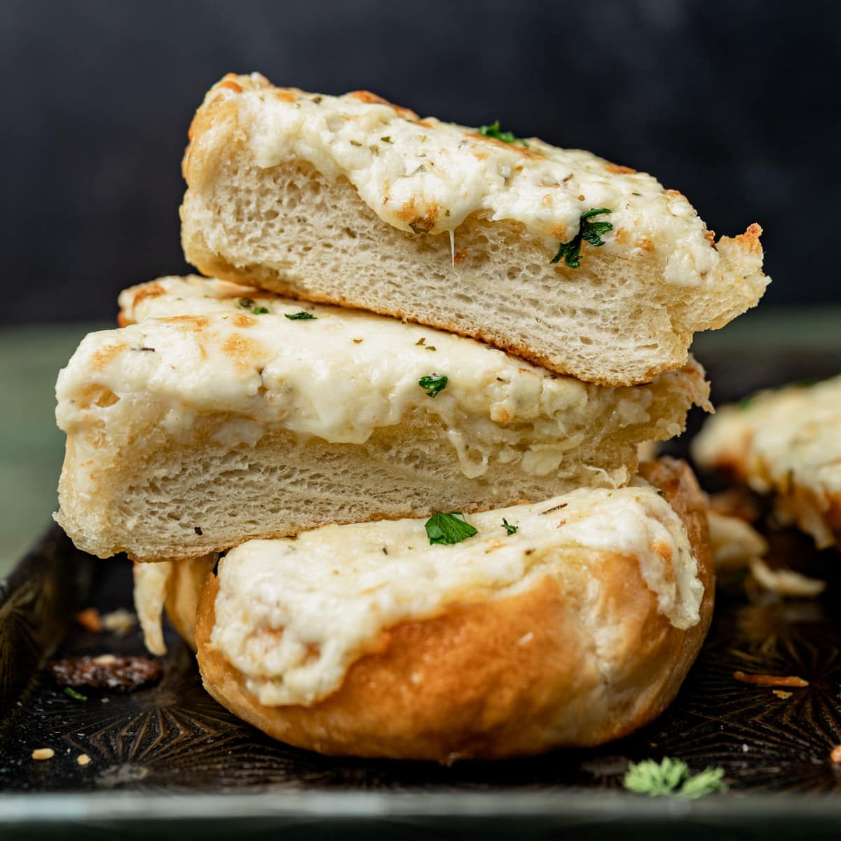 a stack of three pieces of cheesy garlic bread on a pan