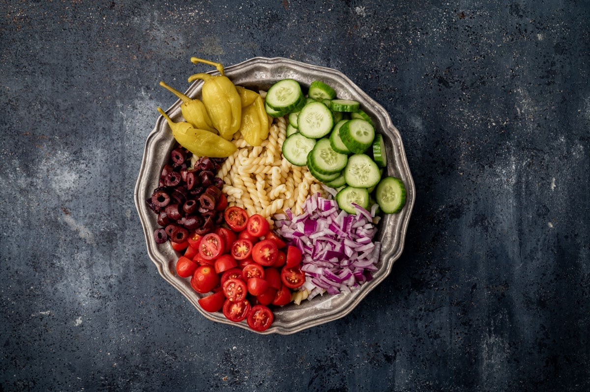 ingredients for greek pasta salad in a bowl