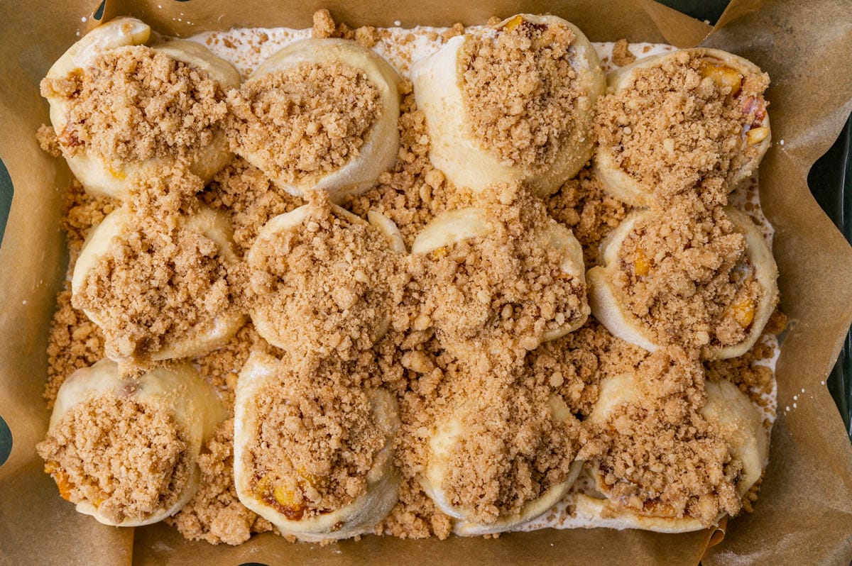 unbaked peach cinnamon rolls with streusel on top in a pan