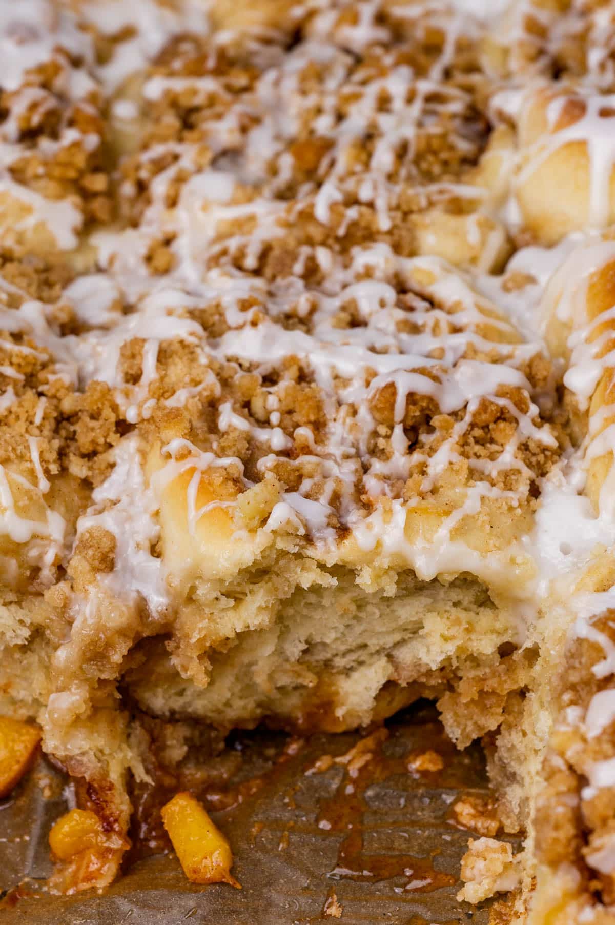 closeup of peach crumble cinnamon rolls in a pan