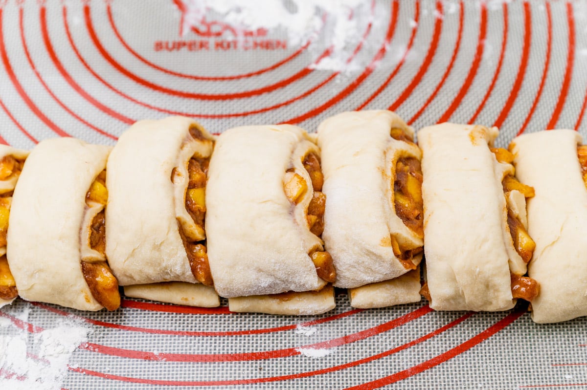 sliced cinnamon roll dough on a baking mat