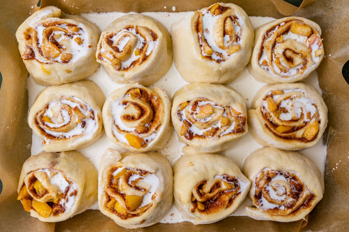 unbaked peach cinnamon rolls with heavy cream poured overtop