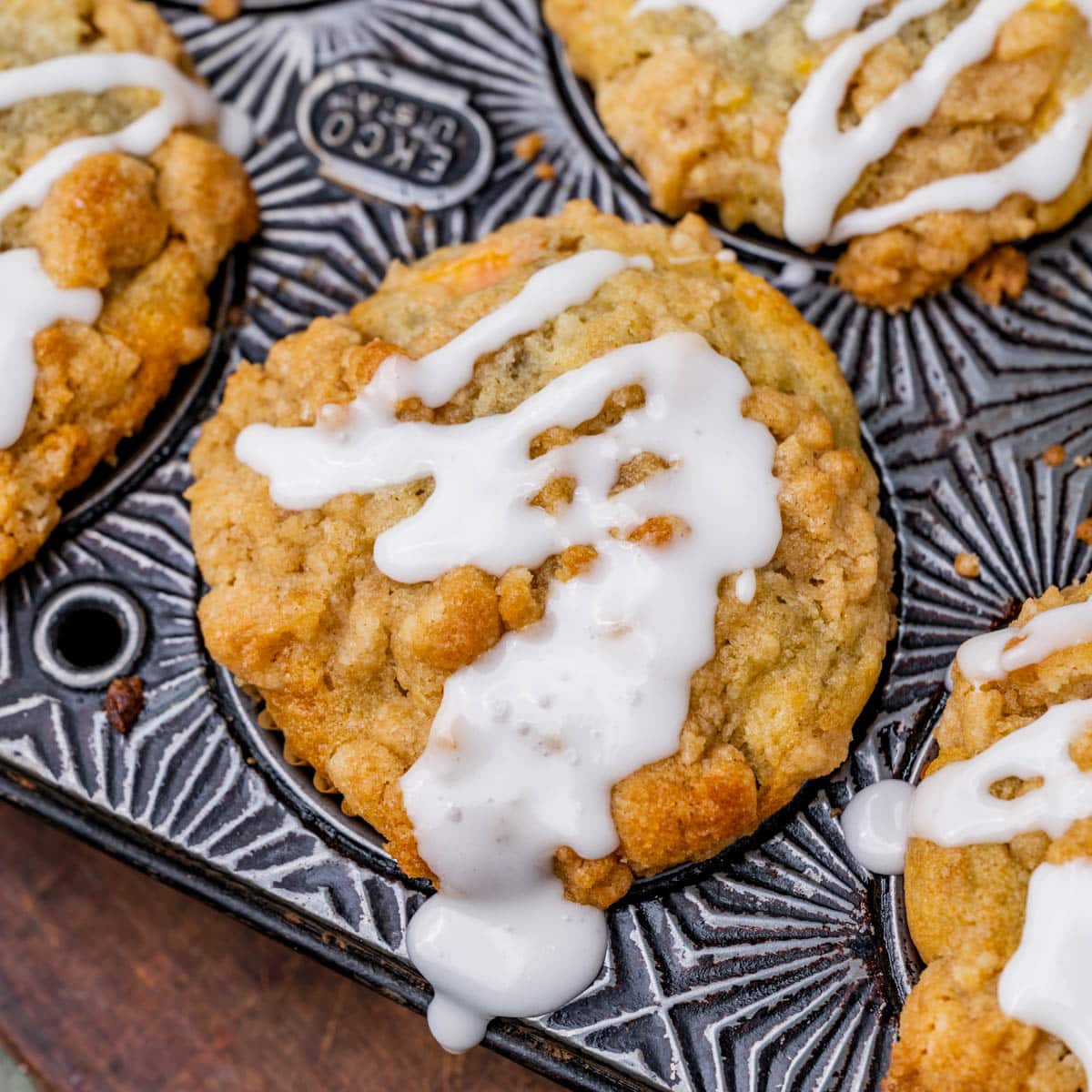 peach crumble muffins with white glaze in a baking pan