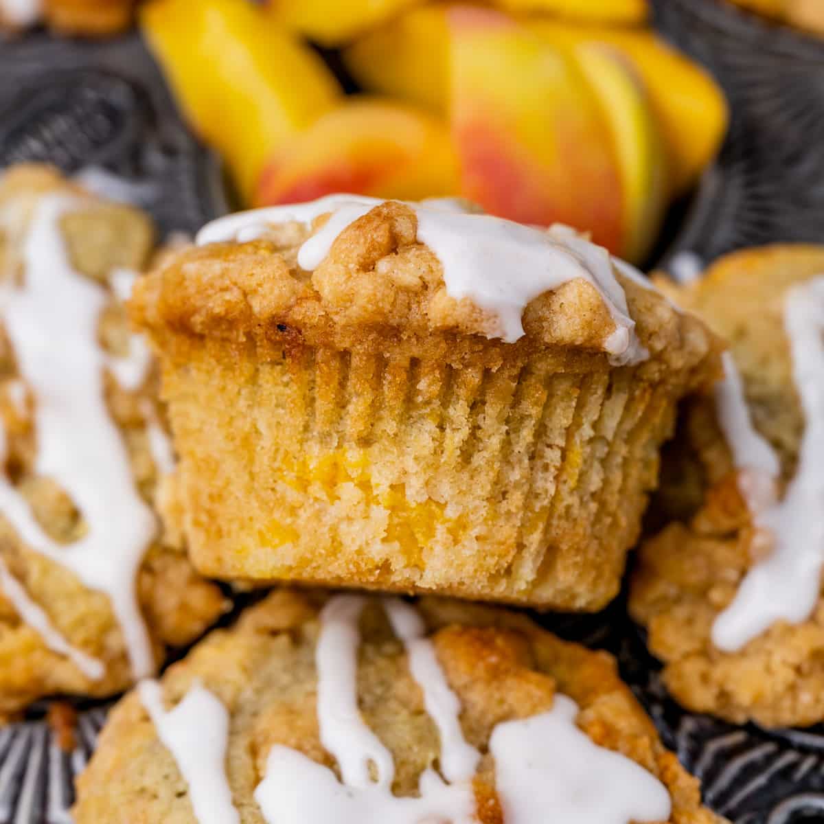 a peach crumble muffin with other muffins in a pan