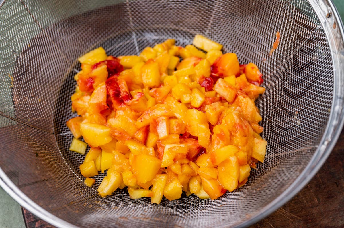 diced peaches in a strainer