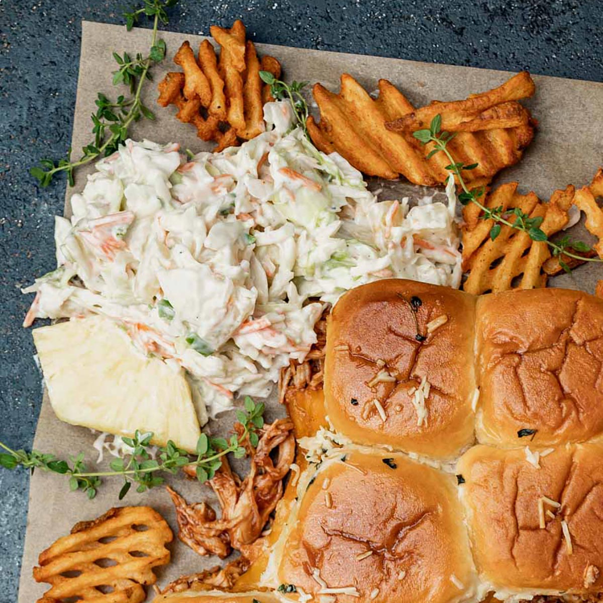pineapple coleslaw, fries and sliders on parchment paper