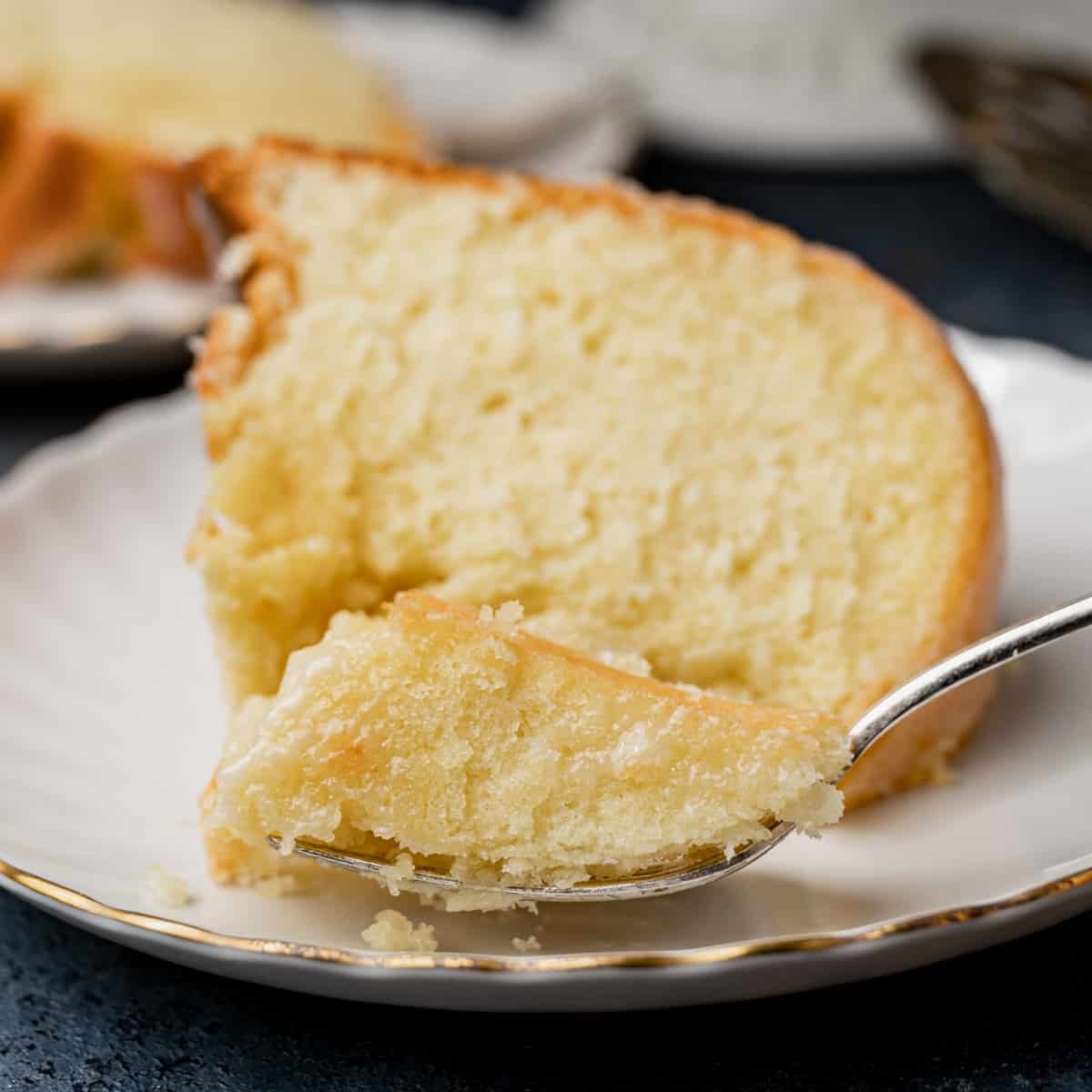a slice of pound cake on a plate with a bite on a fork