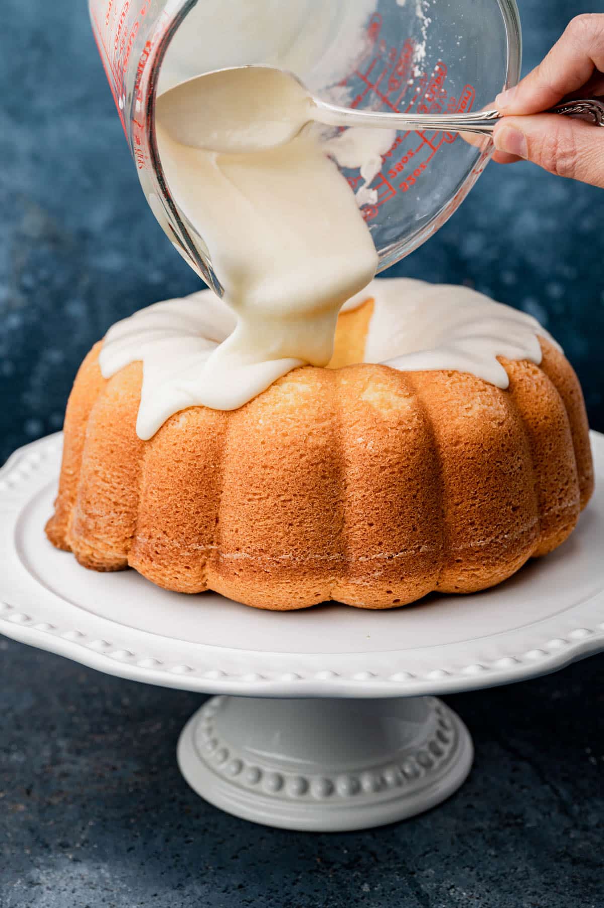 pouring vanilla glaze over a bundt cake