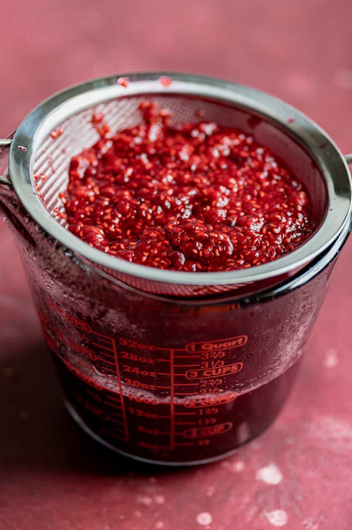 straining raspberry simple syrup from fresh raspberries