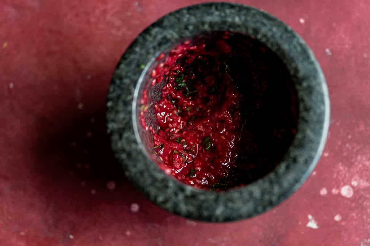 crushed raspberries and mint in a black bowl