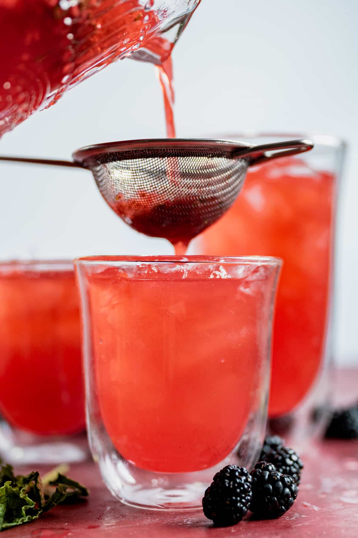straining raspberry puree into a glass