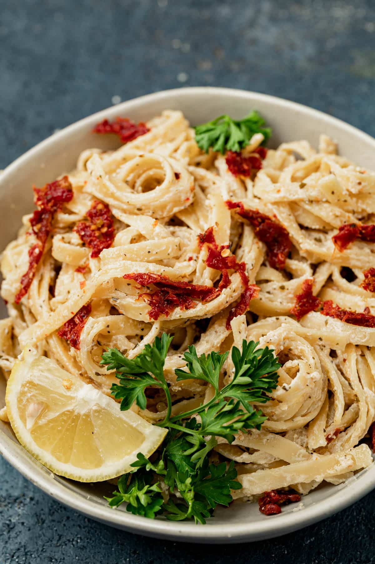 bowl of sun dried tomato pasta with fresh parsley and lemon