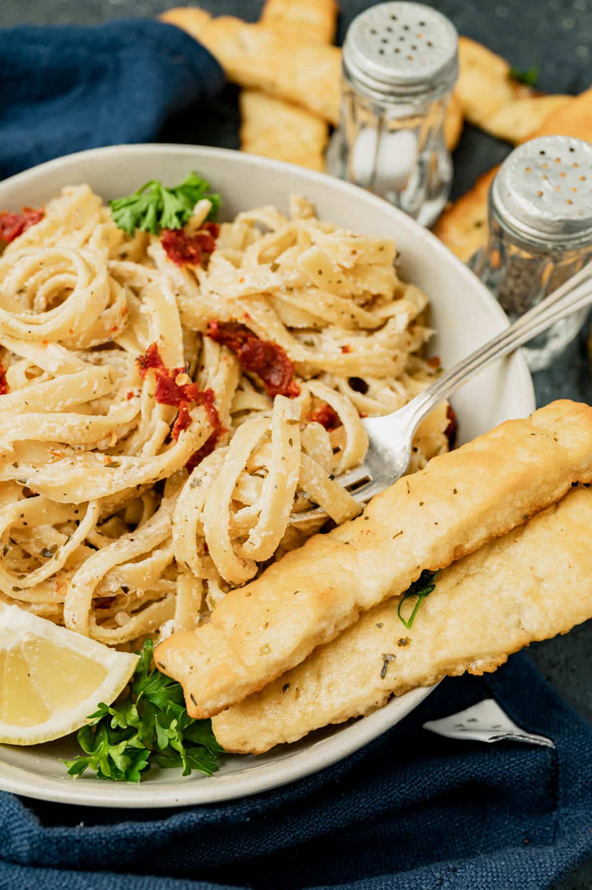 sun dried tomato pasta in a bowl with breadsticks