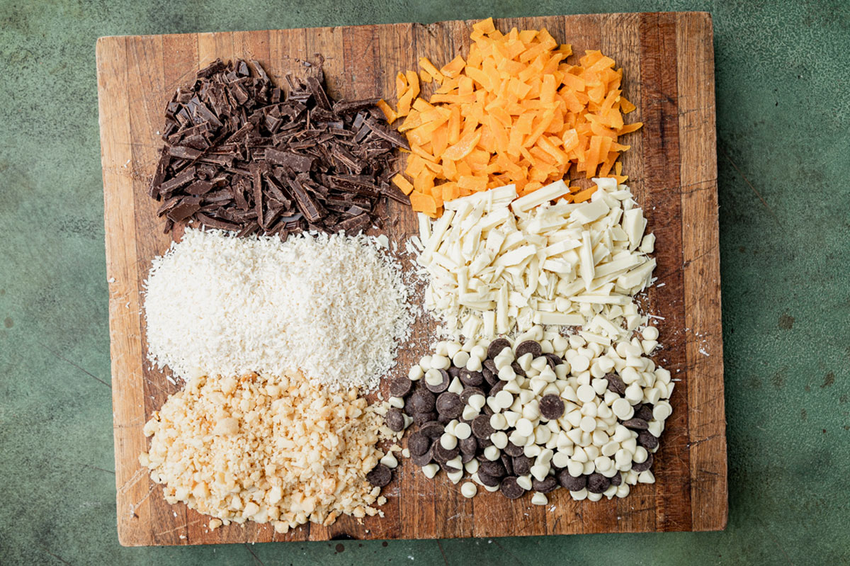 chopped chocolate, mango, coconut and nuts on a cutting board