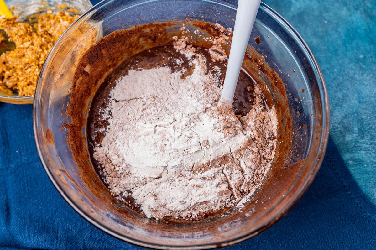 flour over brownie batter in a bowl