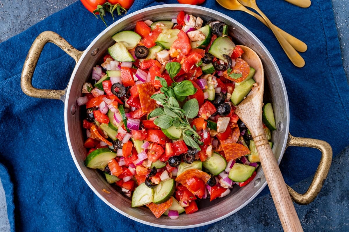 antipasto salad recipe in a bowl with a wooden spoon