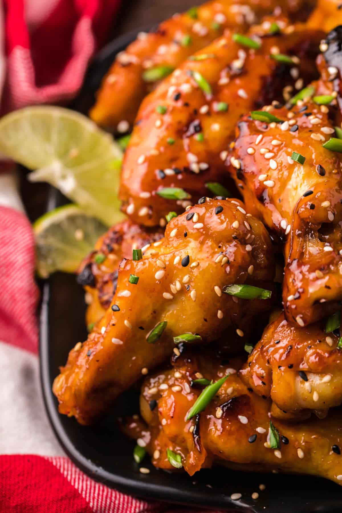 a plate of honey sriracha chicken wings with sesame seeds and chives