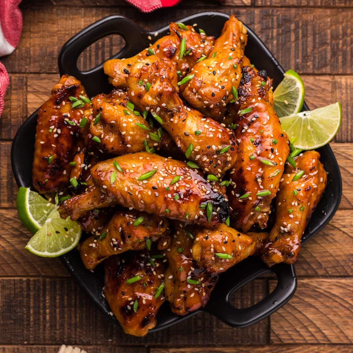 a plate of honey sriracha chicken wings with lime wedges