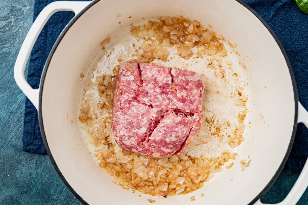 uncooked ground pork in a skillet with sauteed shallot