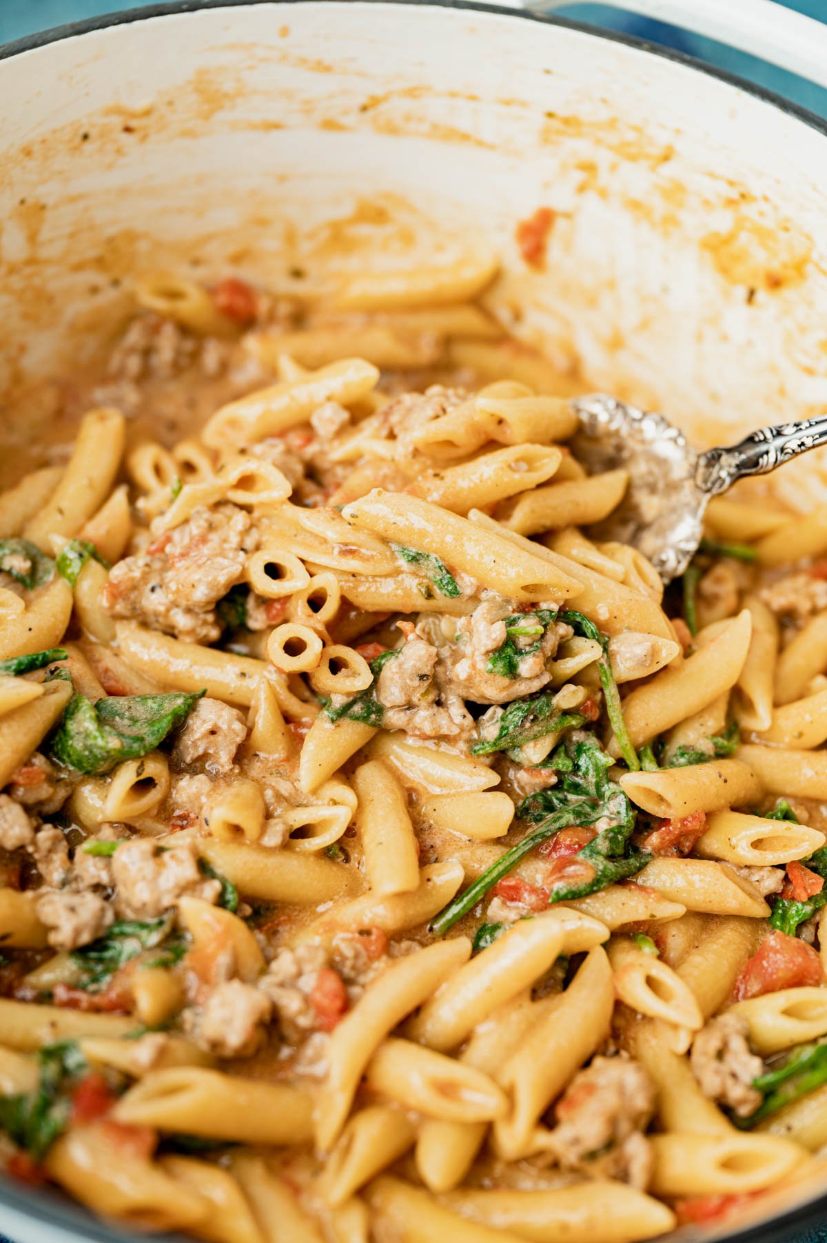 a spoonful of pasta with ground pork, spinach and tomato