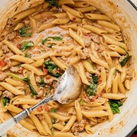 a pot of italian sausage pasta with kale and tomatoes