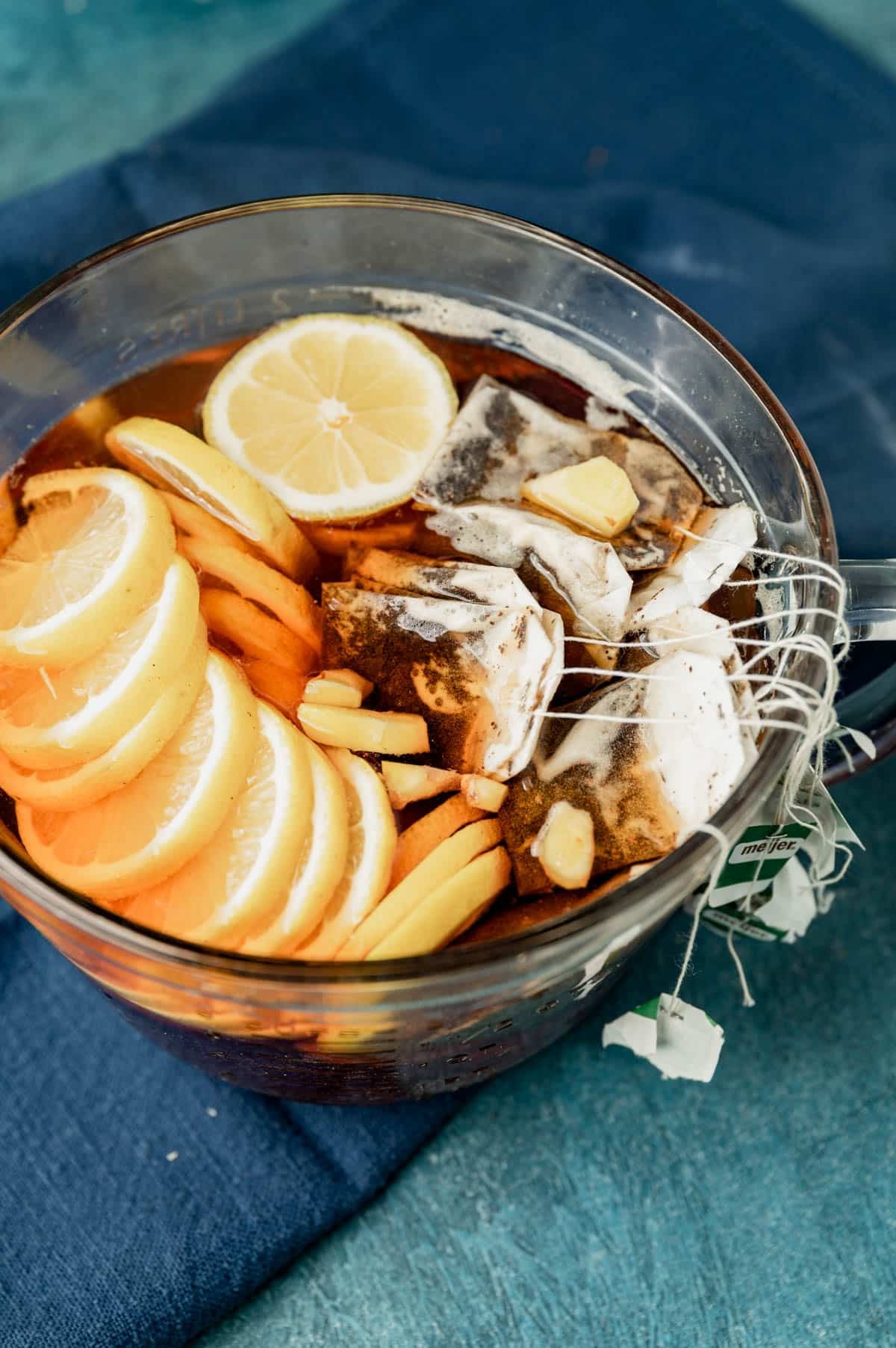 lemons, ginger and tea bags in a bowl of hot water