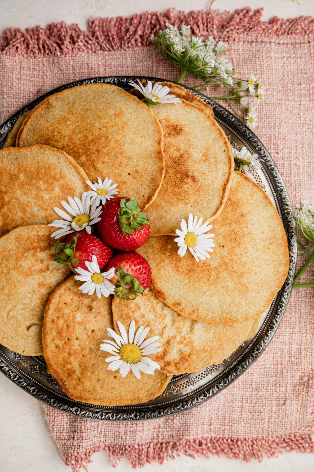 overhead view of a plate of pancakes with strawberries and flowers