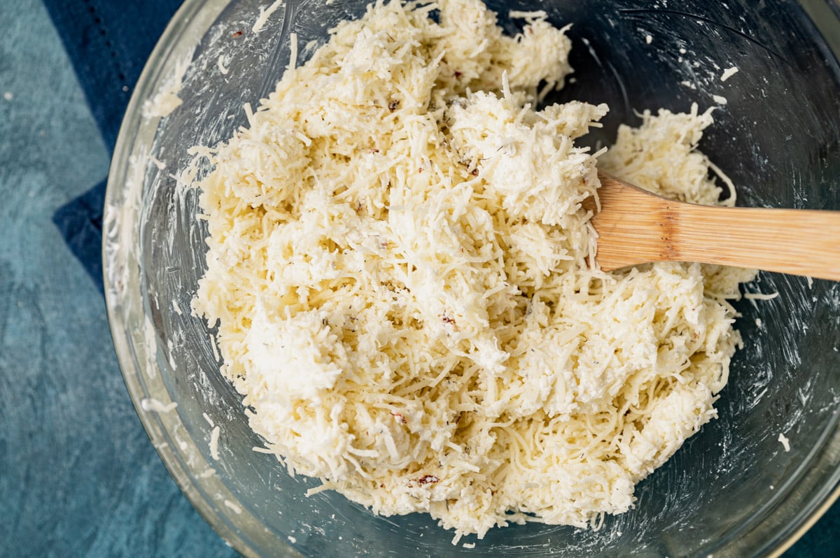 cheese mixture in a glass bowl with a wooden spoon