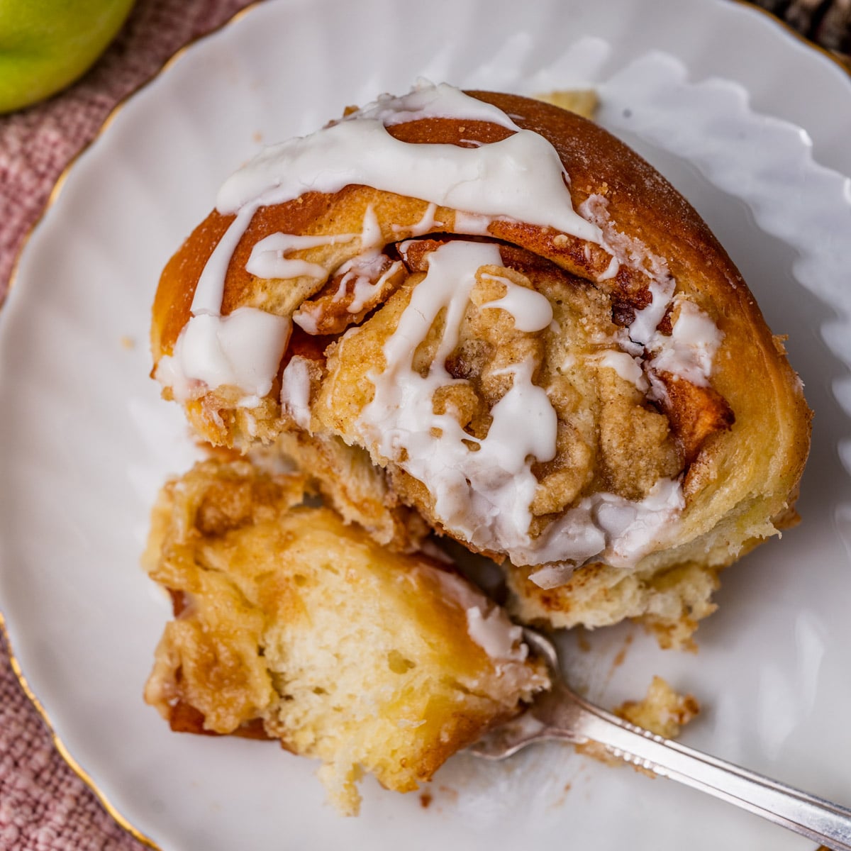 an apple crumble cinnamon roll on a plate with a bite on a fork