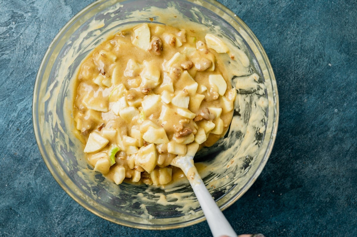 apples and walnuts in a bowl of cake batter
