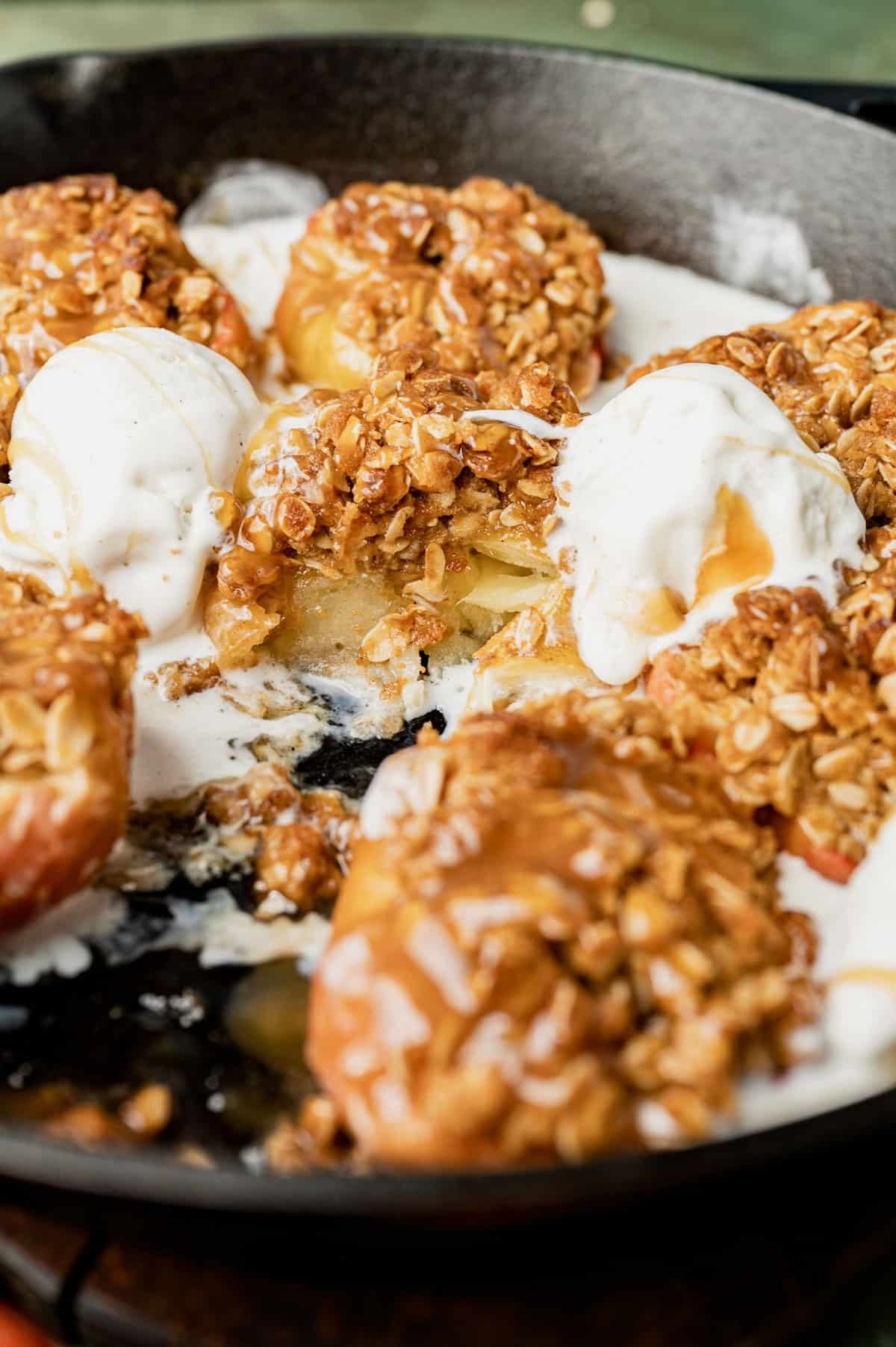a skillet of baked apples with crumble on top and ice cream
