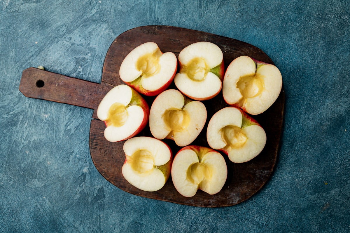 halved and cored apples sitting on a cutting board