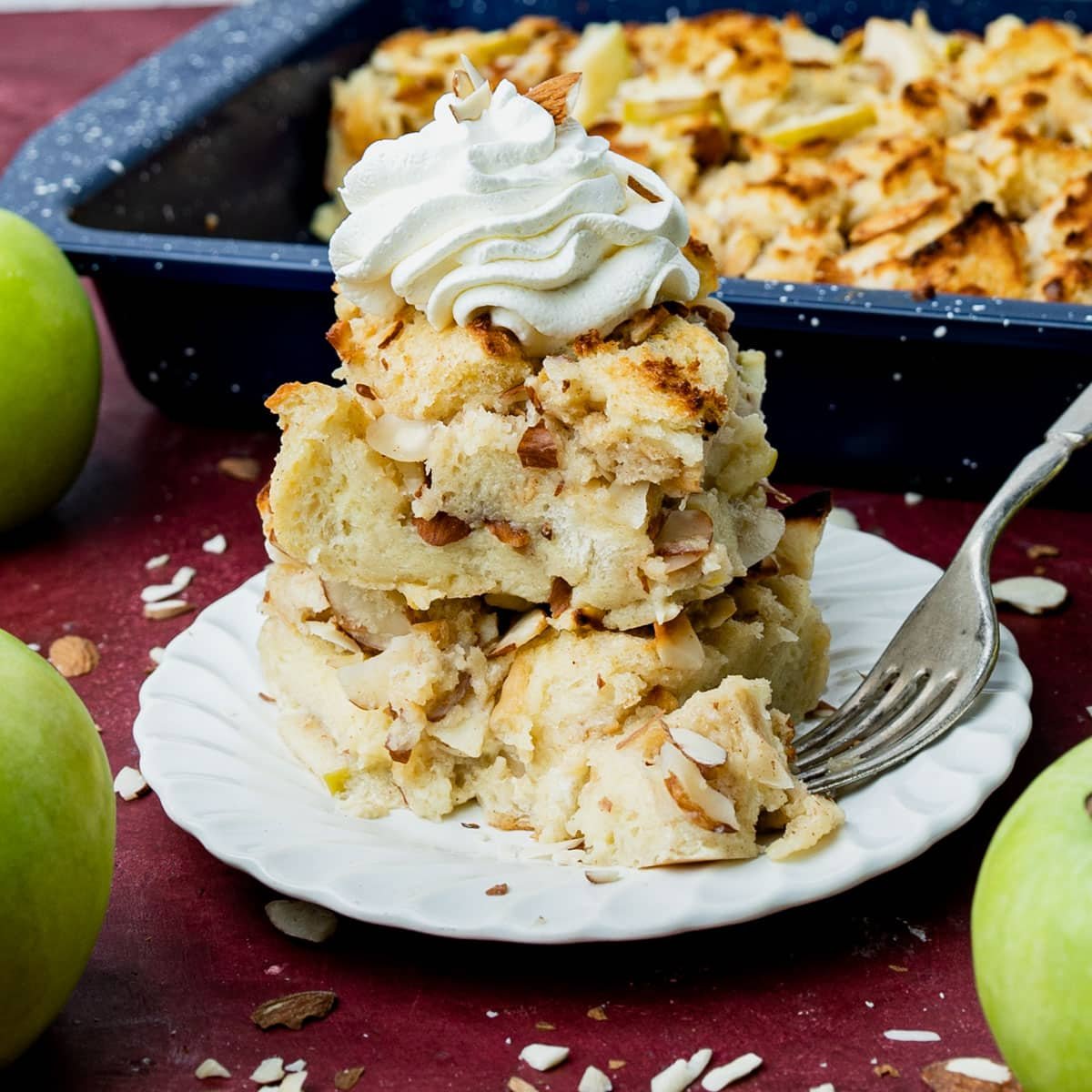 two pieces of apple almond bread pudding stacked on each other with whipped cream