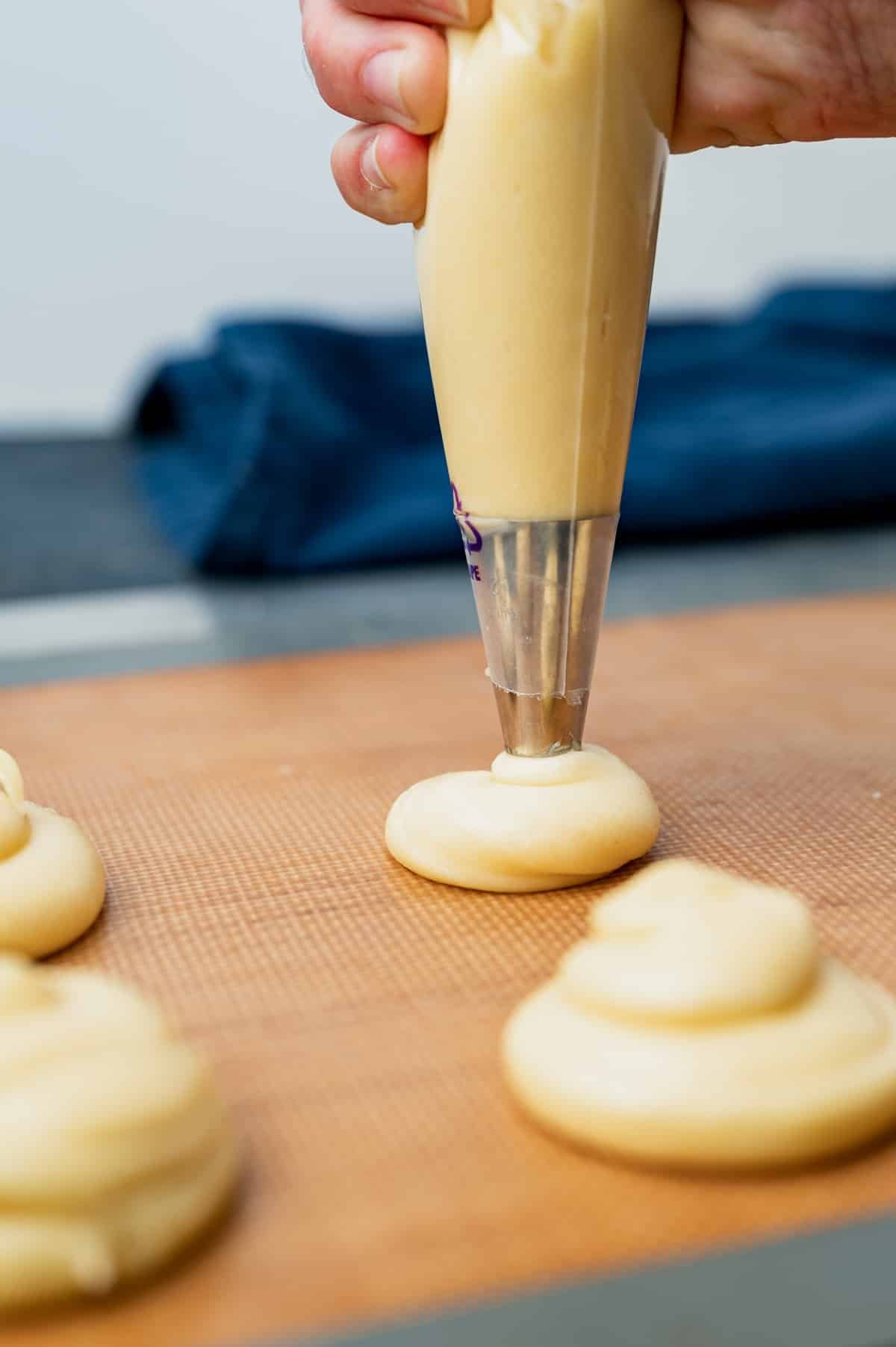 piping cream puff batter onto a baking sheet