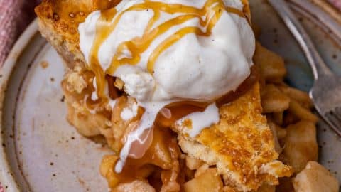 closeup of a piece of apple pie with ice cream and caramel on a plate