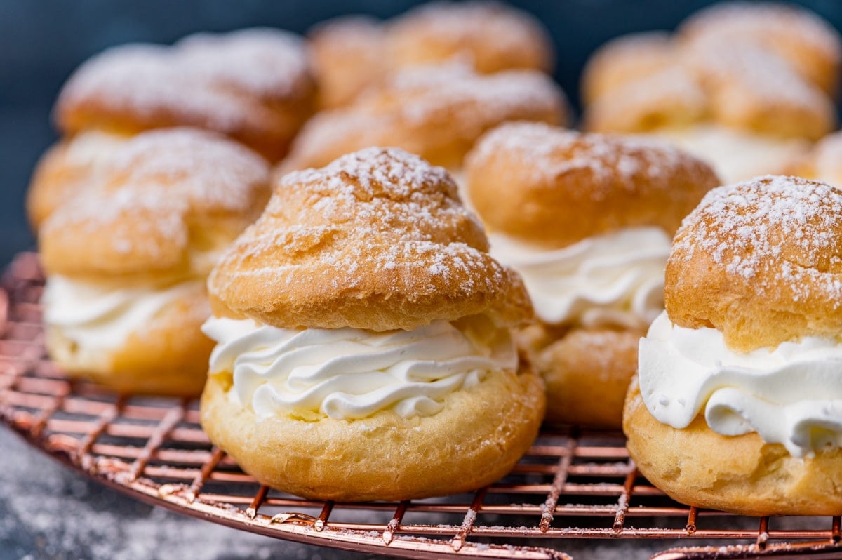 cream puffs filled with whipped cream on a wire rack