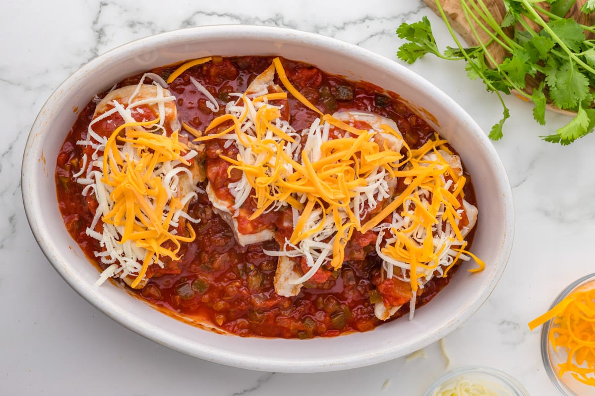 unbaked chicken with salsa and shredded cheese in a dish