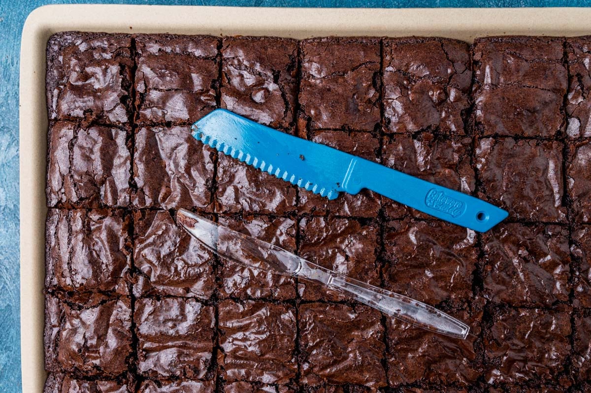 plastic knives sitting on top of brownies in a pan