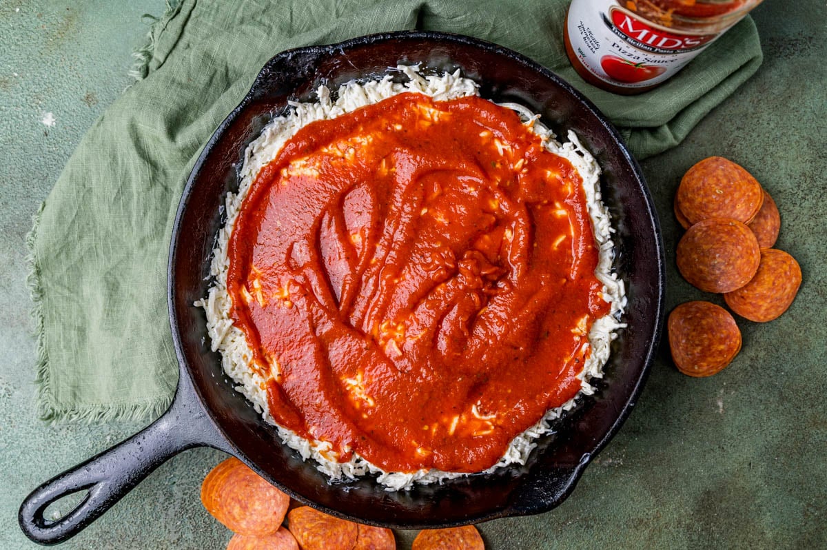 shredded cheese with pizza sauce on top in a skillet