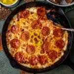 closeup of cast iron cheesy pizza dip with pepperoni on top