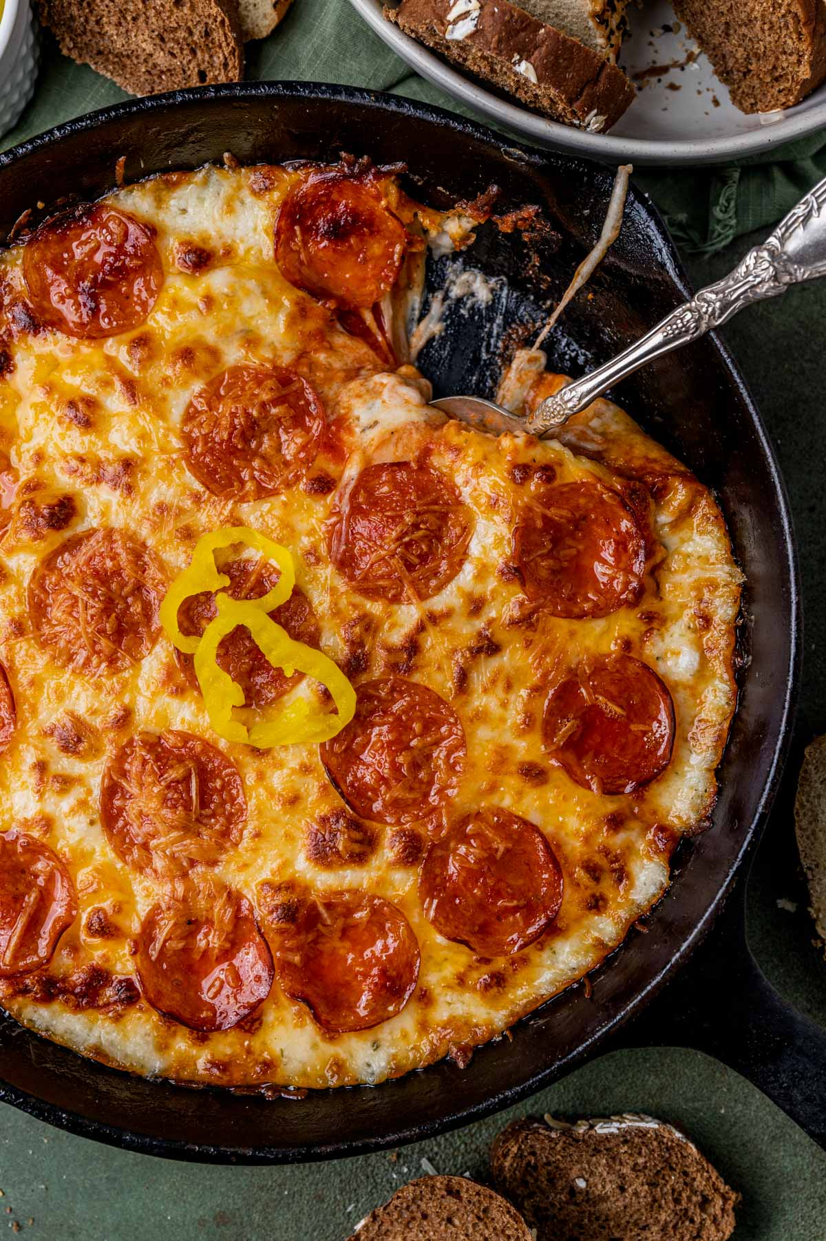 pepperoni pizza dip in a skillet with a spoon