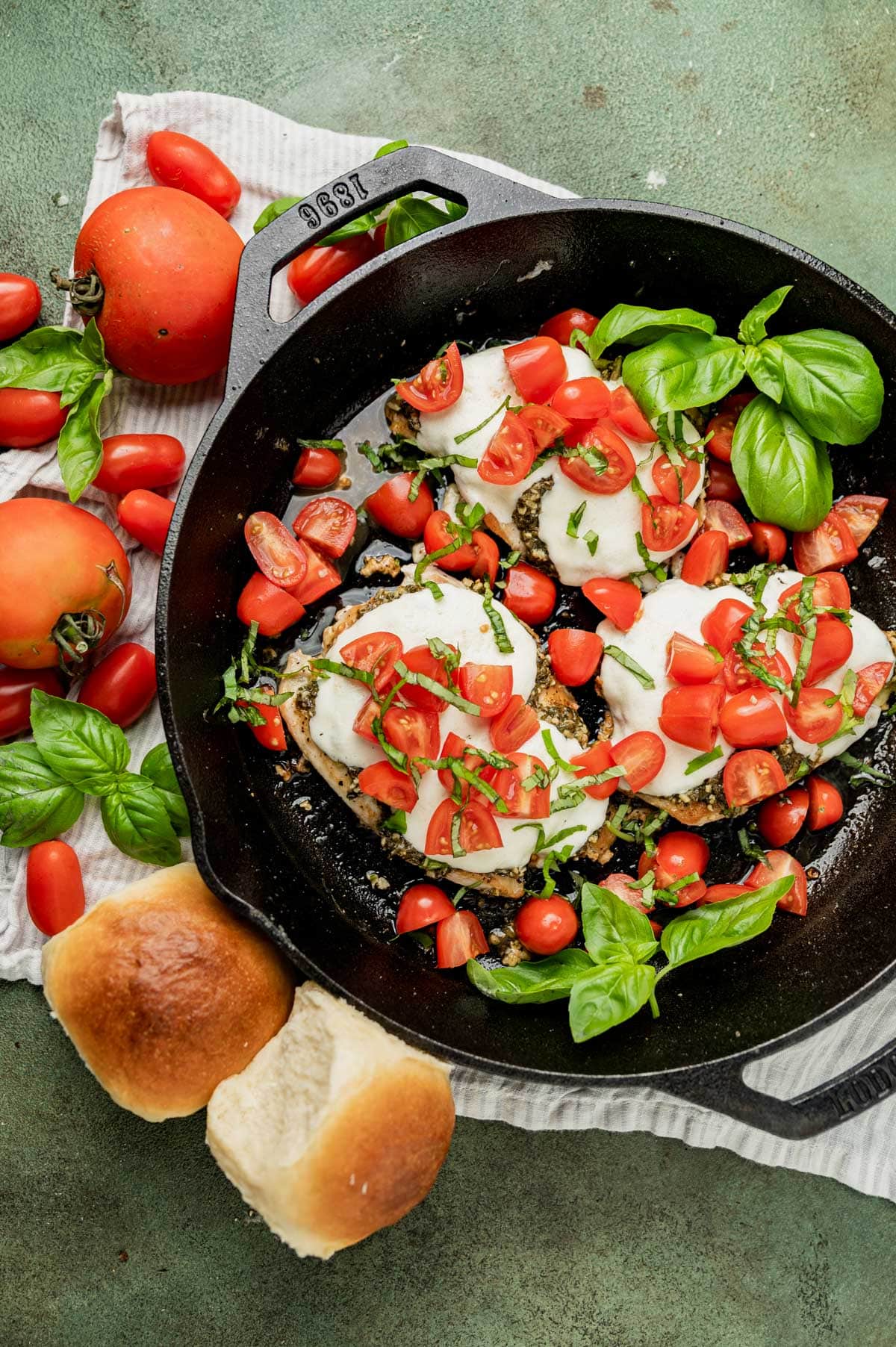 overhead view of a skillet of grilled margherita chicken with rolls