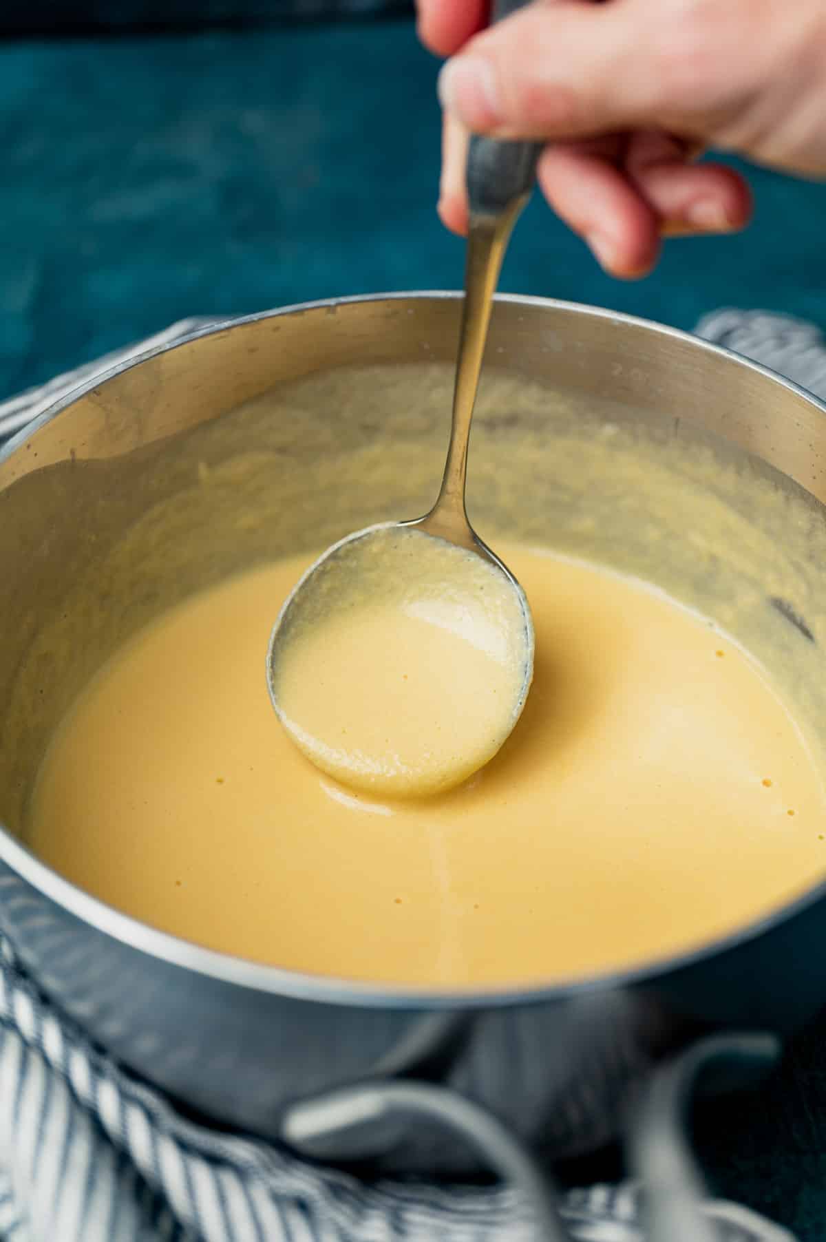 cheese sauce in a saucepan with a ladle