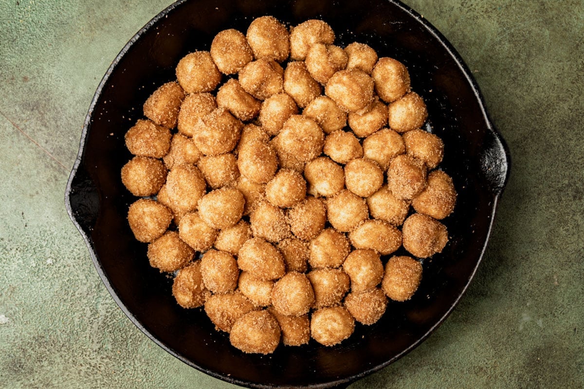 dough balls rolled in butter and sugar in a cast iron skillet