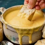 bread dipping into a bowl of cheese sauce