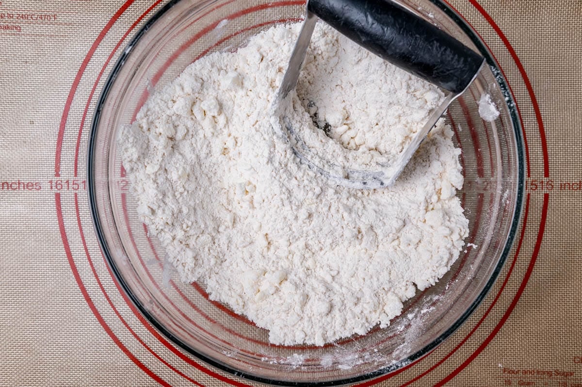 a pastry cutter in a bowl with flour and butter