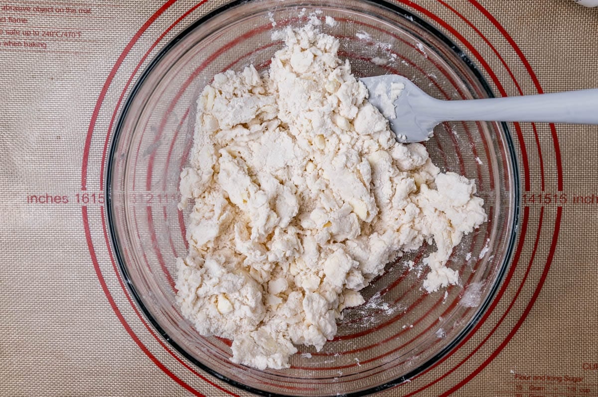 unmixed pie dough in a bowl with a spatula