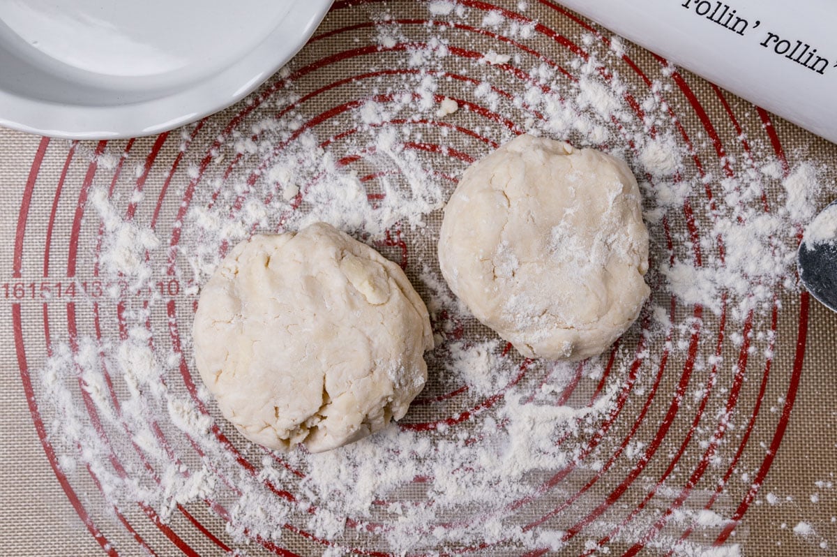 two balls of pie dough on a floured pastry mat