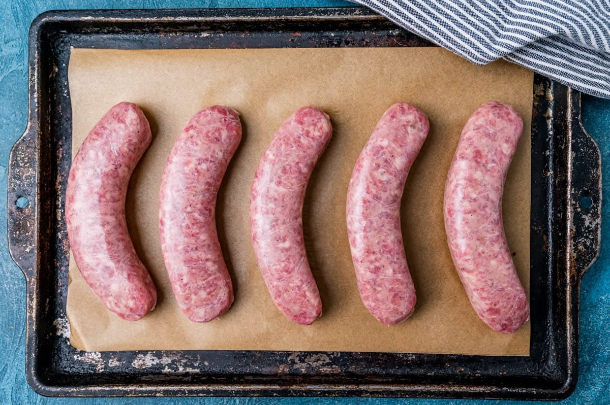 uncooked bratwurst on a baking pan